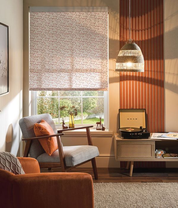 White and orange patterned roller blind in a sitting room with orange panelled walls and ambient golden lighting